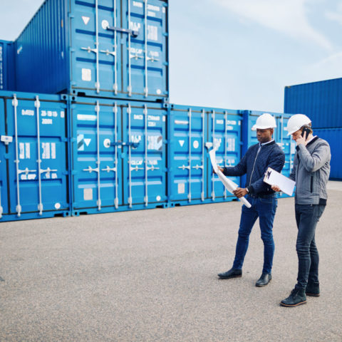 Two engineers standing in a freight yard discussing building plans