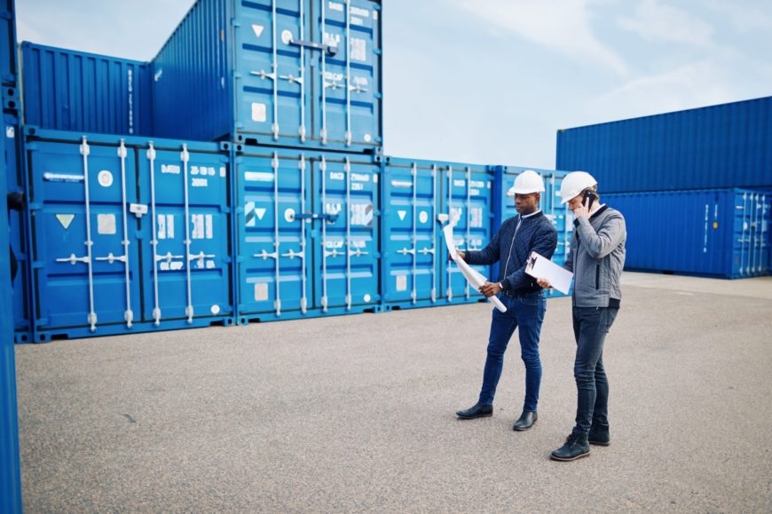 Two engineers standing in a freight yard discussing building plans